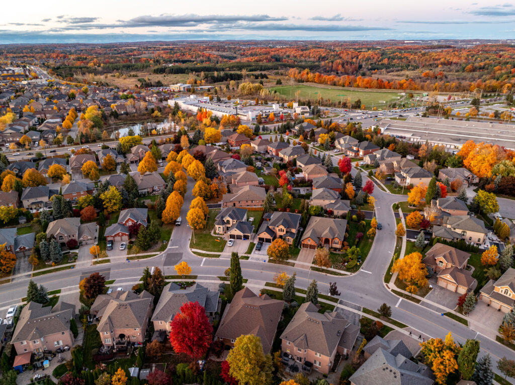 Aerial view of a suburban neighborhood in the fall season with homes, garages, and bright autumn foliage.