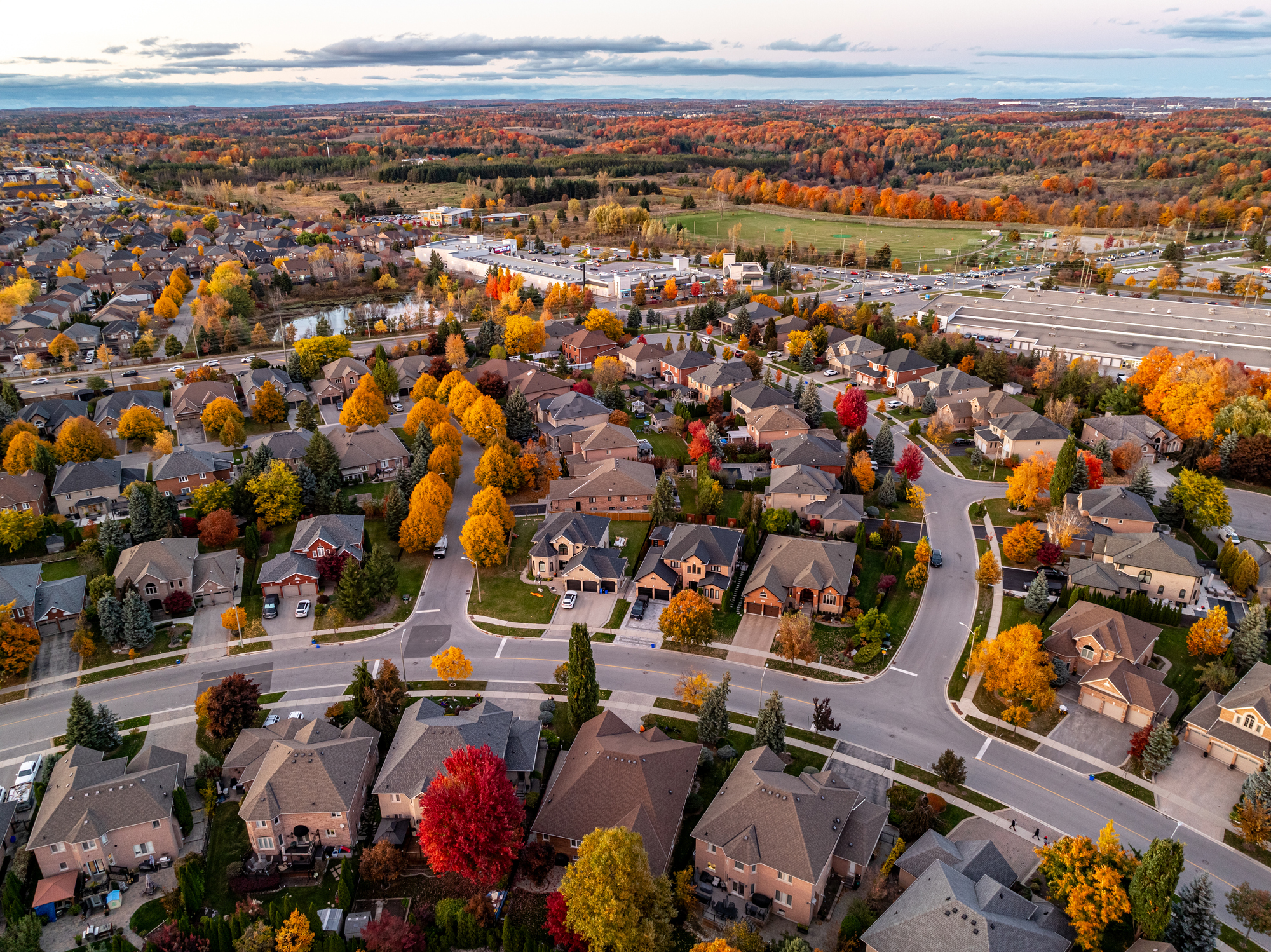 Aerial view of a suburban neighborhood in the fall season with homes, garages, and bright autumn foliage.